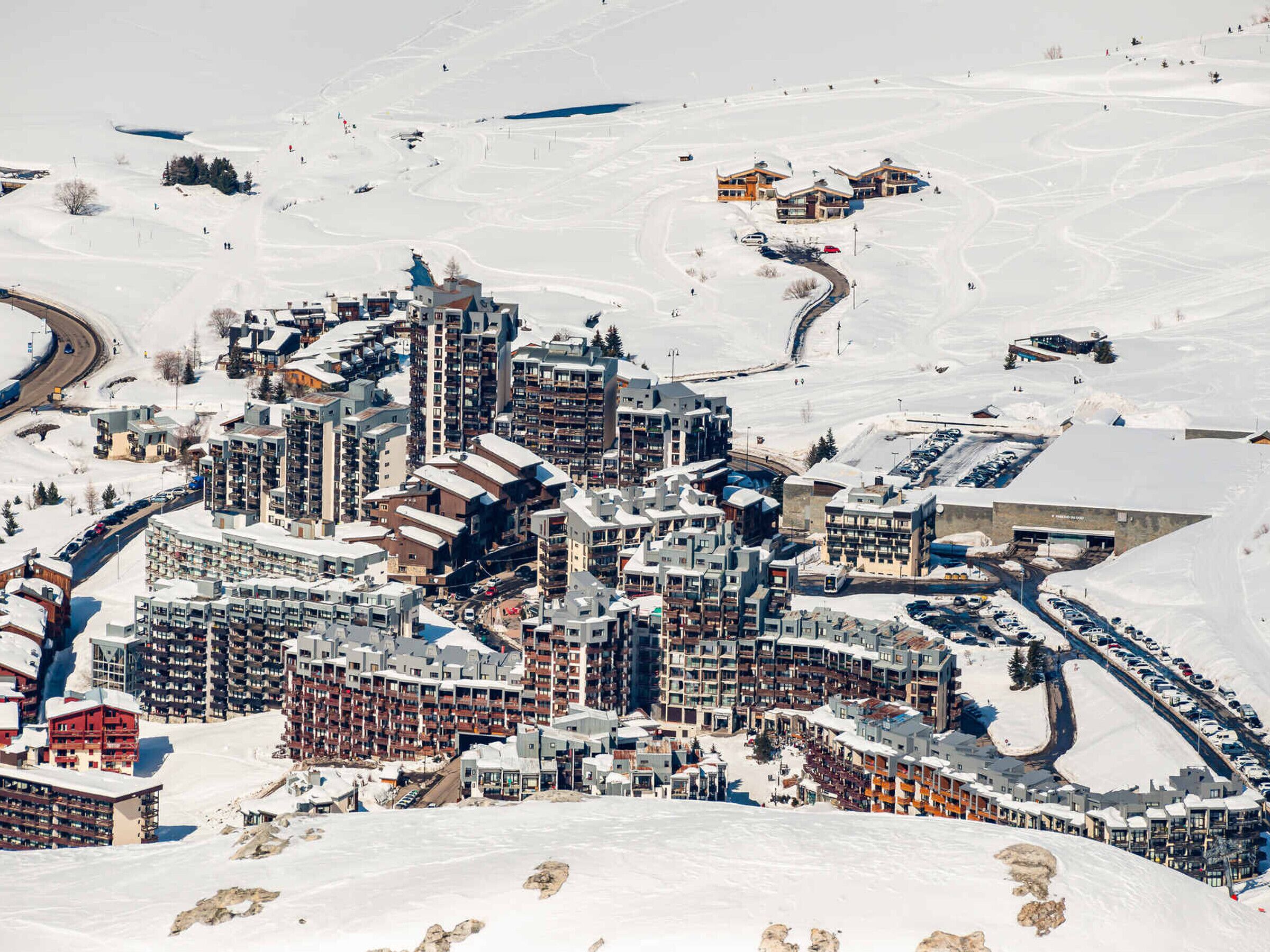 Un pueblo cubierto de nieve con un conjunto denso de edificios de varios pisos, carreteras y una pista de esquí.