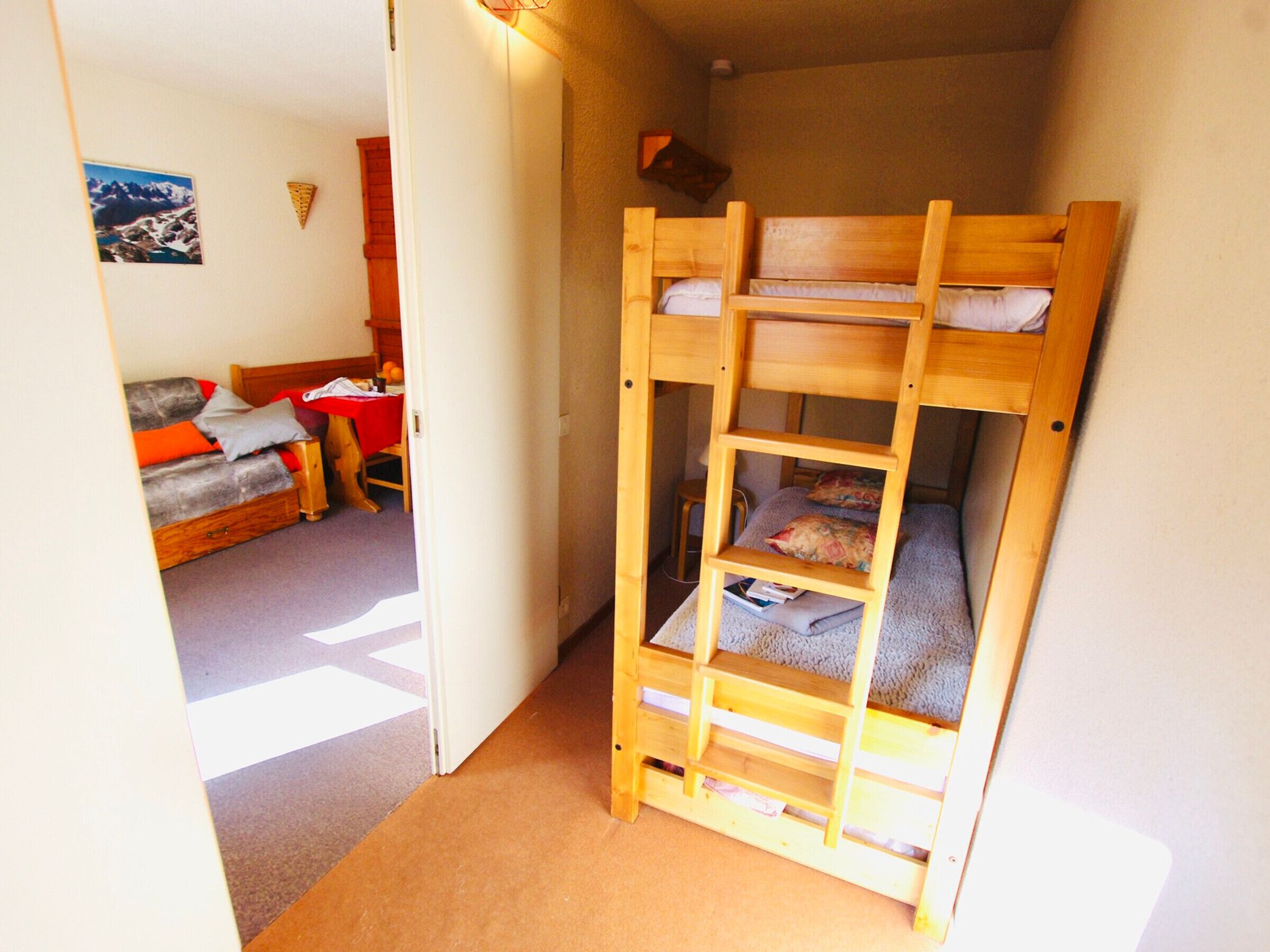 Een kleine, smalle kamer met een stapelbed en een bureau.