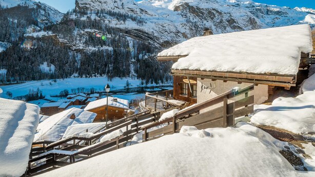 A snow-covered mountain landscape with a wooden building featuring a staircase and a sign that reads "WILDER." - 5* Chalet in Tignes: 6 rooms, sauna, jacuzzi, parking (Tignes-Les Brévières)
