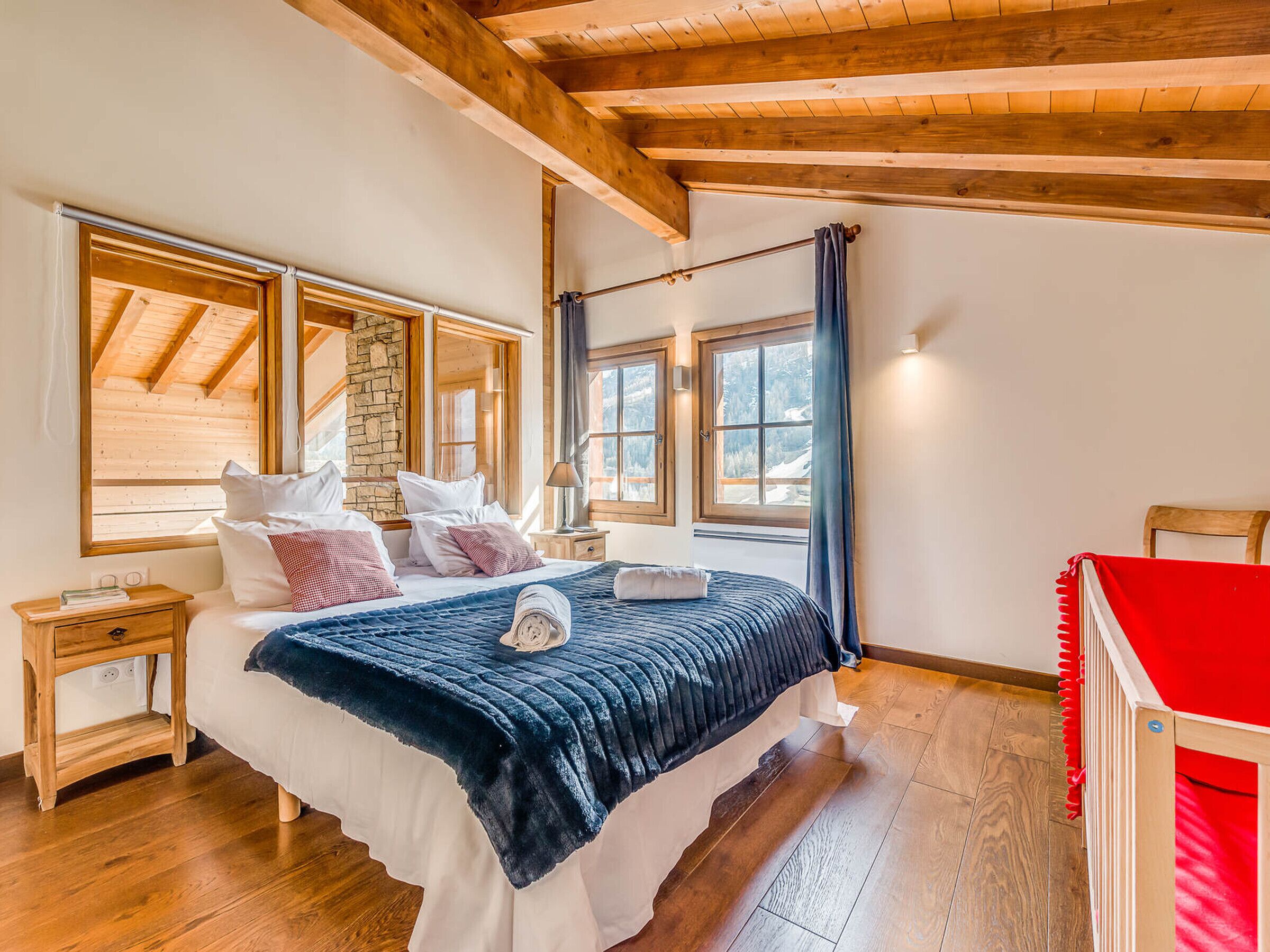 Une chambre avec un plafond en bois, un mur en pierre et de grandes fenêtres.