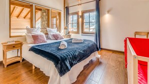 A bedroom with a wooden ceiling, a stone wall, and large windows. - 5* Chalet in Tignes: 6 rooms, sauna, jacuzzi, parking (Tignes-Les Brévières)