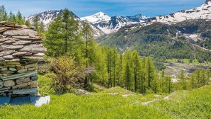 A stone structure with a view of snow-capped mountains and a forested valley. - 5* Chalet in Tignes: 6 rooms, sauna, jacuzzi, parking (Tignes-Les Brévières)
