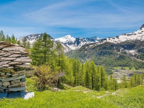 A stone structure with a view of snow-capped mountains and a forested valley.