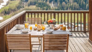 A wooden deck with a table set for breakfast, overlooking a mountainous landscape. - 5* Chalet in Tignes: 6 rooms, sauna, jacuzzi, parking (Tignes-Les Brévières)