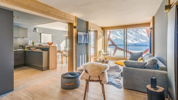 Ein moderner Wohnraum mit Küche, Essbereich und großem Fenster mit Bergblick.