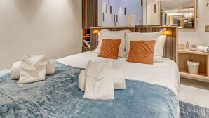A modern hotel room with a large bed, a skylight, a vanity with a mirror, and a nightstand. - Tignes: Renovated apt, 7 pers, 3 rooms, included services (Tignes)