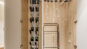 A room with a wooden door, a metal rack with multiple black and green objects, and a metal grid door. - Tignes: Renovated apt, 7 pers, 3 rooms, included services (Tignes)