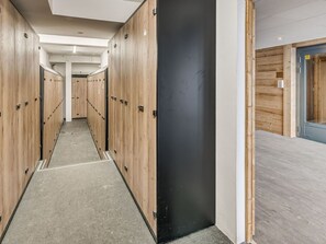 A corridor with lockers, a black door, and a wooden wall.