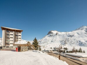 A snow-covered mountain with a ski resort building and a small structure in the foreground. - Renovated 3* apartment with terrace, lake view, sleeps 6, WiFi included (Tignes)