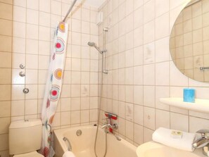 Een badkamer met een bad, douche, toilet en wastafel.