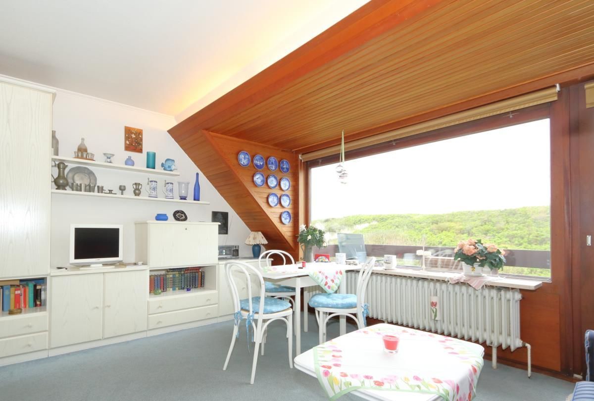 Una habitación acogedora con una mesa de comedor, sillas, un televisor y una estantería.