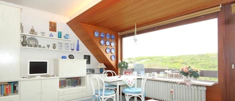 A cozy room with a dining table, chairs, a TV, and a bookshelf.