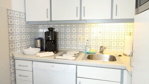 A compact kitchen with white cabinets, a stainless steel sink, and a coffee maker. - App. Feusser - at Wenningstedter Strand (Wenningstedt-Braderup (Sylt))