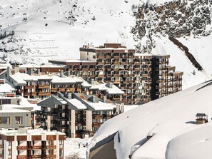 Une ville de montagne enneigée, avec des immeubles modernes à plusieurs étages, dont un hôtel doté de balcons.