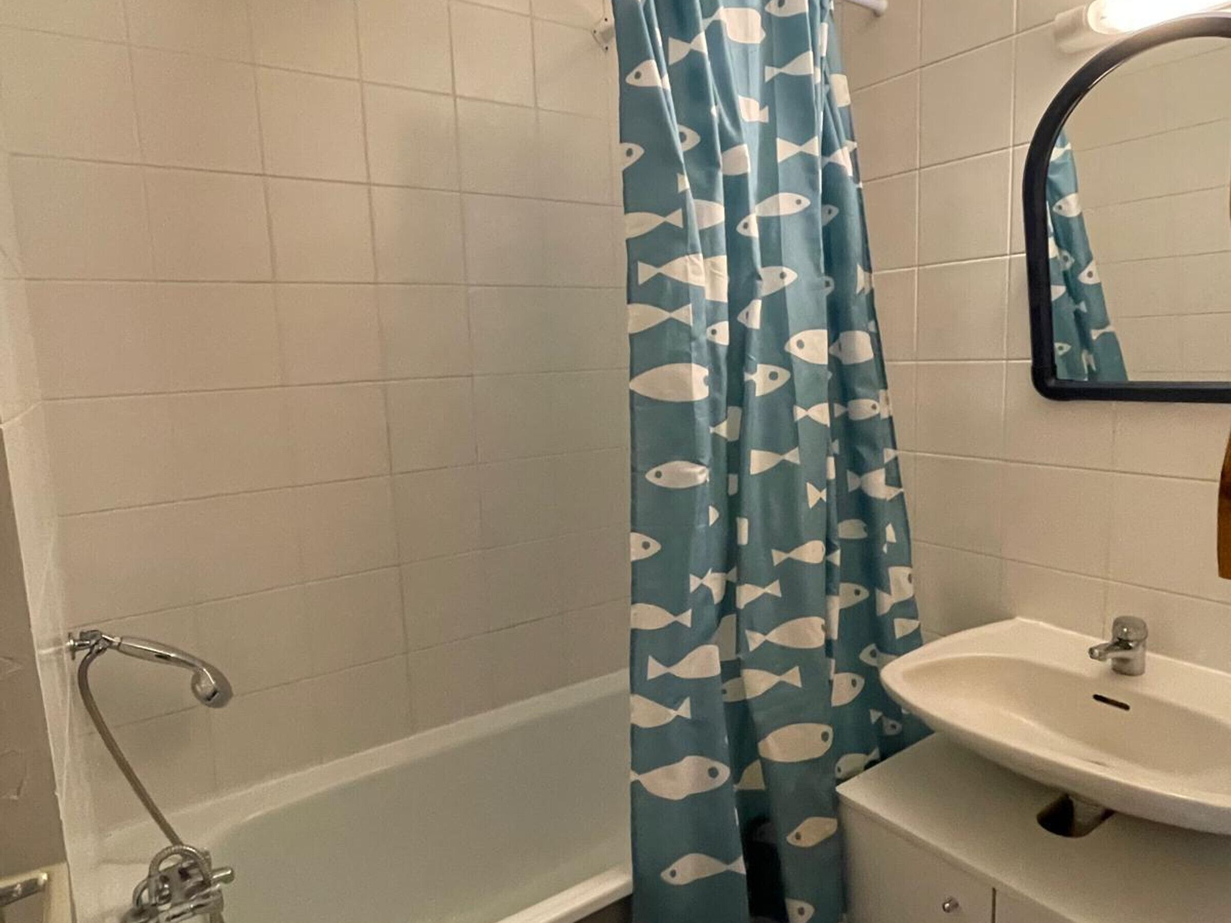 A bathroom with a bathtub, a sink, and a mirror.