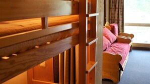 A wooden bunk bed with a mattress and pillows, a window with curtains, and a carpeted floor. - Large studio for 4 - Comfortable with balcony (Tignes)