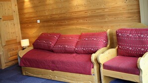 A wooden room with a bed, two chairs, and a nightstand with a lamp. - Large studio for 4 - Comfortable with balcony (Tignes)