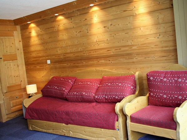 A wooden room with a bed, two chairs, and a nightstand with a lamp. - Large studio for 4 - Comfortable with balcony (Tignes)