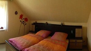 Un dormitorio con dos camas, una mesita de noche, un aparador y una ventana con cortinas.