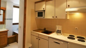 Una cucina compatta con forno a microonde, macchina del caffè, piano cottura e lavastoviglie.
