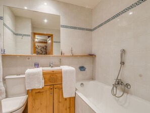 Een badkamer met een houten kast, twee wastafels, een toilet, een bad en een douche.