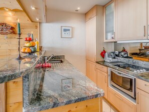 A kitchen with granite countertops, wooden cabinets, a sink, a stove, and a microwave. - 3* Apartment cozy, comfortable, 7 pers, lake view (Tignes)
