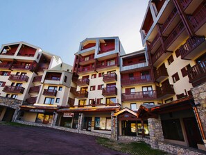 A multi-story hotel with balconies, a stone facade, and signage for a restaurant and a bar.