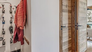 Un corridoio con una porta in legno, un portascarpe a parete e pavimento piastrellato.