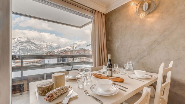 A dining table set with plates, glasses, a bottle of wine, and a loaf of bread, overlooking a snowy mountain landscape. - Renovated comfy studio 4 ppl with balcony in Tignes (Tignes)