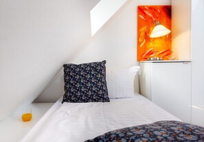 Een moderne hotelkamer met een bed, een kussen, een nachtkastje met een glas sinaasappelsap en een wandlamp.