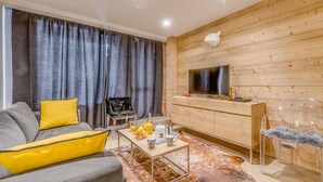 A modern living room with a sofa, coffee table, and a TV on a wooden wall.