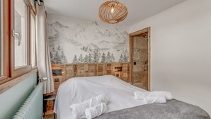 A bedroom with a bed, a radiator, a wooden headboard, a wall mural, and a hanging light fixture. - Premium 3-room apartment, lake view, 6 pers., WIFI, in Tignes (Tignes)