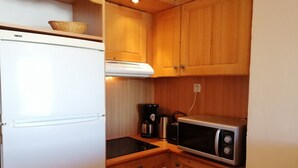 A compact kitchen with a refrigerator, stove, microwave, and a coffee maker.