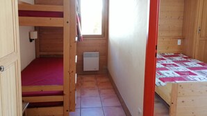 A compact room with a bunk bed, a small window, and a heater.
