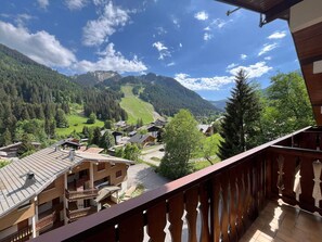 A balcony with a view of a mountain village, wooden buildings, and a clear sky. - Cozy apartment for 4 with balcony and garage in Châtel (Châtel)