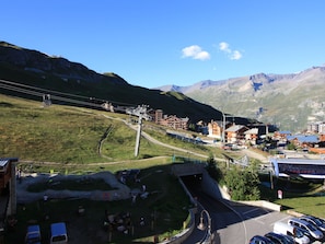 A mountainous town with a ski lift, buildings, and a parking area.
