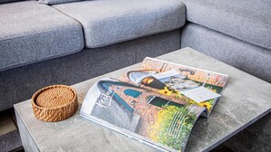Un sofá gris con una cesta tejida sobre una mesa gris.