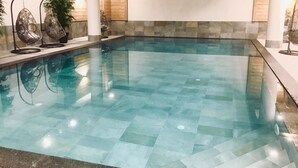 A large indoor swimming pool with a tiled floor and a stone wall backdrop. - Premium 4* Apartment Ski-in/Ski-out with SPA and Parking (Tignes-Les Boisses)