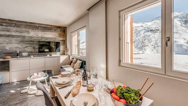 Una cucina moderna con zona pranzo, ampie finestre vista montagne innevate e un angolo relax.