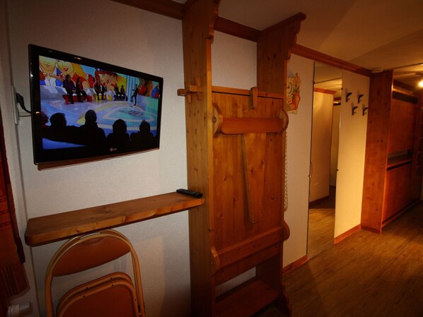 Ein Korridor mit Holzwänden und einem an der Wand befestigten Fernseher, der ein Programm zeigt.