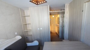 A compact room with a sofa, a small table, and a wardrobe with a mirror. - Renovated Studio for 2 - Tignes (Tignes)