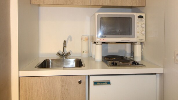Una kitchenette compacta con un lavamanos, un microondas y un refrigerador pequeño.