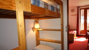 Habitación con literas, cabecero de madera, lámpara de pared y suelo cubierto de moqueta roja.