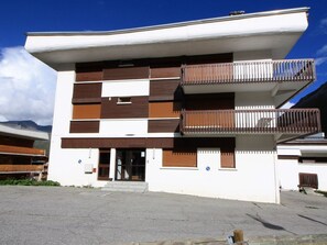 A modern building with a flat roof, multiple balconies, and a central entrance.