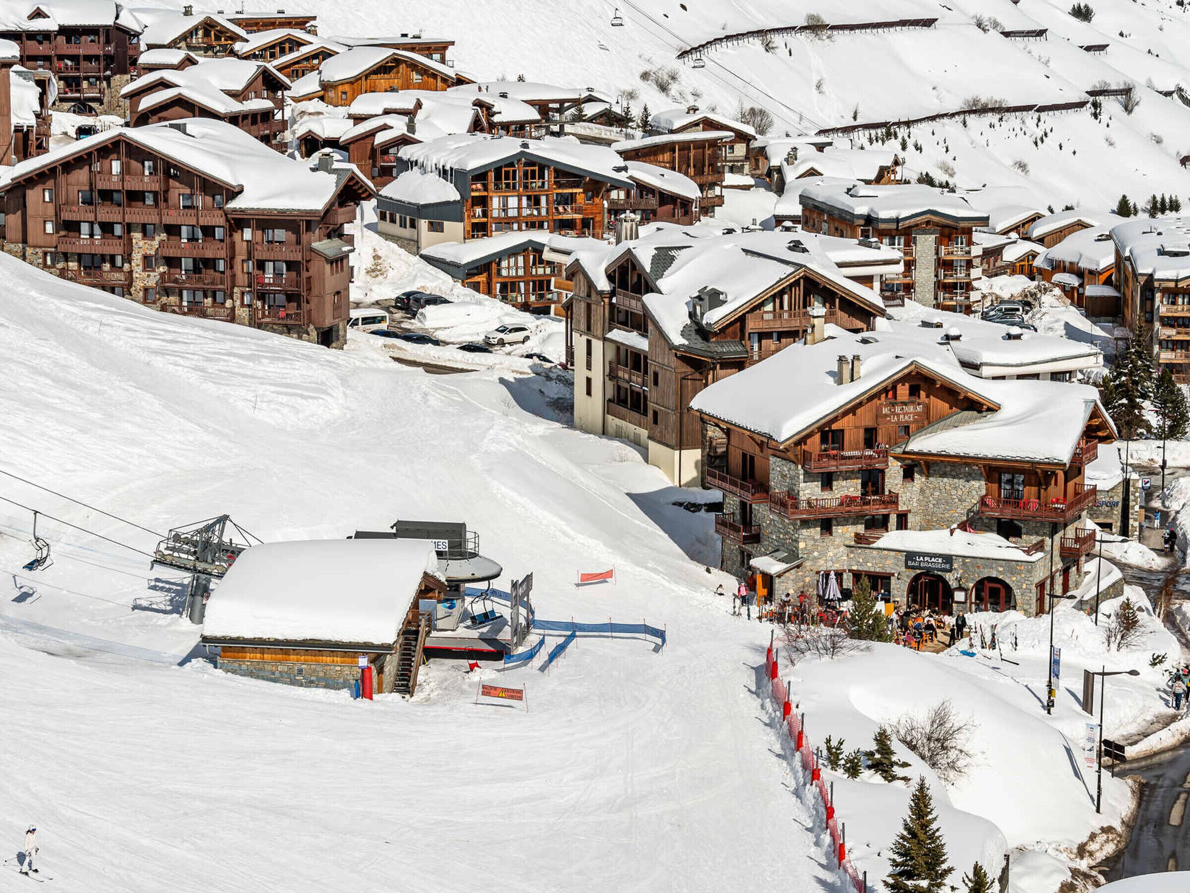 Un centro de esquí cubierto de nieve con edificios de madera y un telesilla.