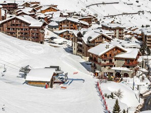A snow-covered ski resort with wooden buildings and a ski lift.