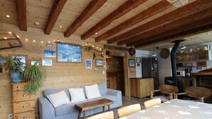 Una stanza accogliente con soffitto in legno, un divano, un tavolo da pranzo e un angolo cottura.