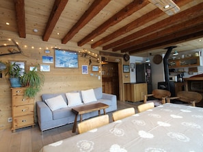 Ein gemütliches Zimmer mit Holzboden, einer Couch, einem Esstisch und einer Küchenzeile.