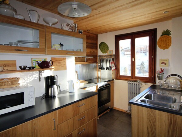 Eine Küche mit Holzausstattung, einer Mikrowelle, einer Kaffeemaschine und einem Fenster mit Blick nach draußen.