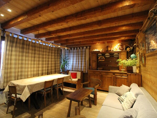A cozy wooden interior with a dining area, sofa, and kitchen cabinetry.